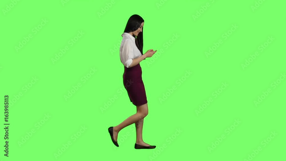 Girl of asian appearance walks the street, the phone looks at interesting pictures. Green screen.cc Girl of asian appearance walks the street, the phone looks at interesting pictures. Green screen.cc