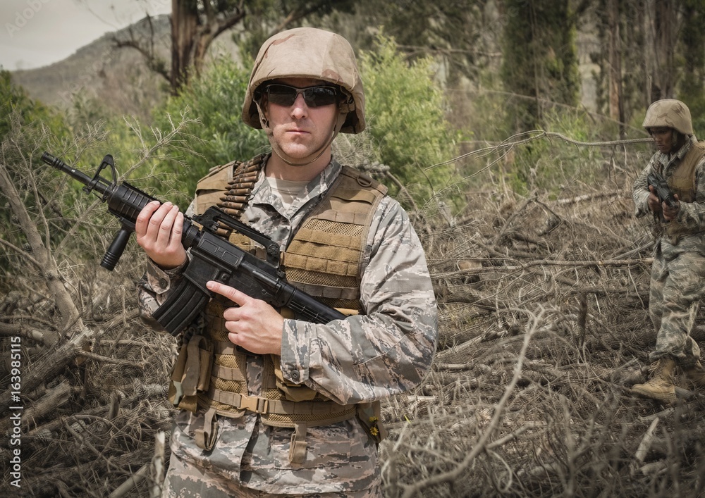 Soldier man holding a weapon against field background