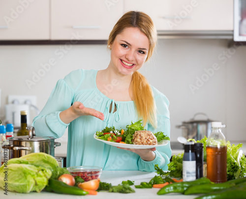 Young housewife with plate of cheese and salad