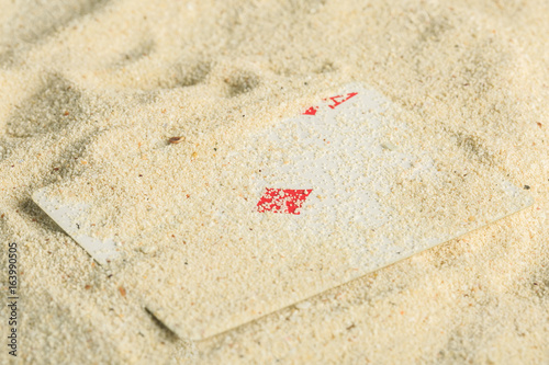 Poker playing cards buried in a sand dune