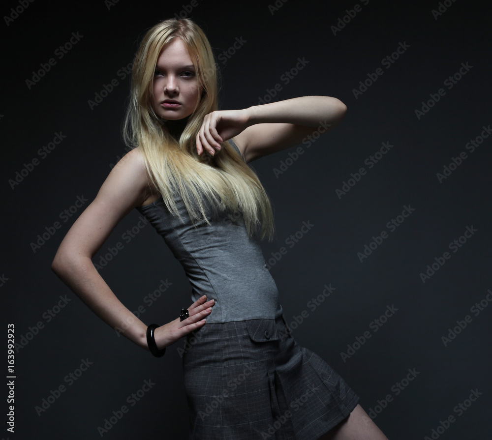 Fototapeta premium Portrait of beautiful young blonde girl in black dress. 