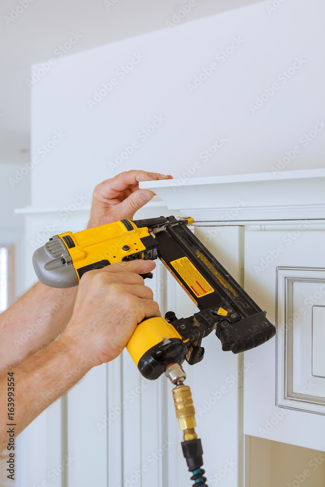 Carpenter brad using nail gun to Crown Moulding on kitchen cabinets framing trim, Carpenter brad using nail gun to Crown Moulding on kitchen cabinets framing trim,
