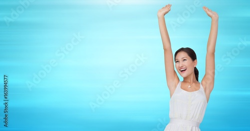 Woman in white dress celebrating against blurry blue background