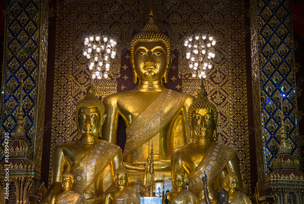Fototapeta premium The Buddha statue in viharn of Wat Phra That Hariphunchai the iconic famous temple in Lamphun city, Northern Thailand.
