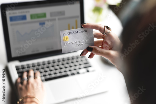 Woman Hand Holding Platinum Credit Card with Laptop Background