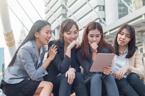 Group of businesswoman using the tablet for business connection with her partner in downtown with building background