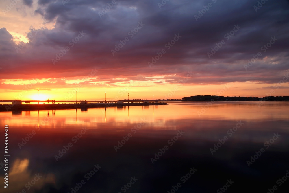 Summer sunset over the lake. Beautiful landscape with dramatic golden sunset after evening storm on a lake Mendota in the city of Madison, Wisconsin, USA. Long exposure horizontal shot.