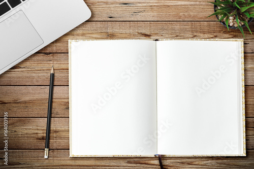 Top view of blank notebook, laptop and little tree page on wood background office desk with different objects. Minimal flat lay style
