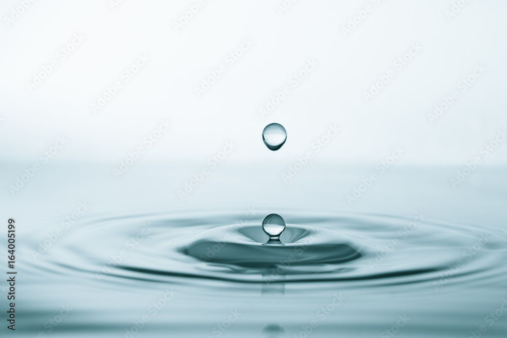 Water drop and splash on water surface on blue background Water drop and splash on water surface on blue background
