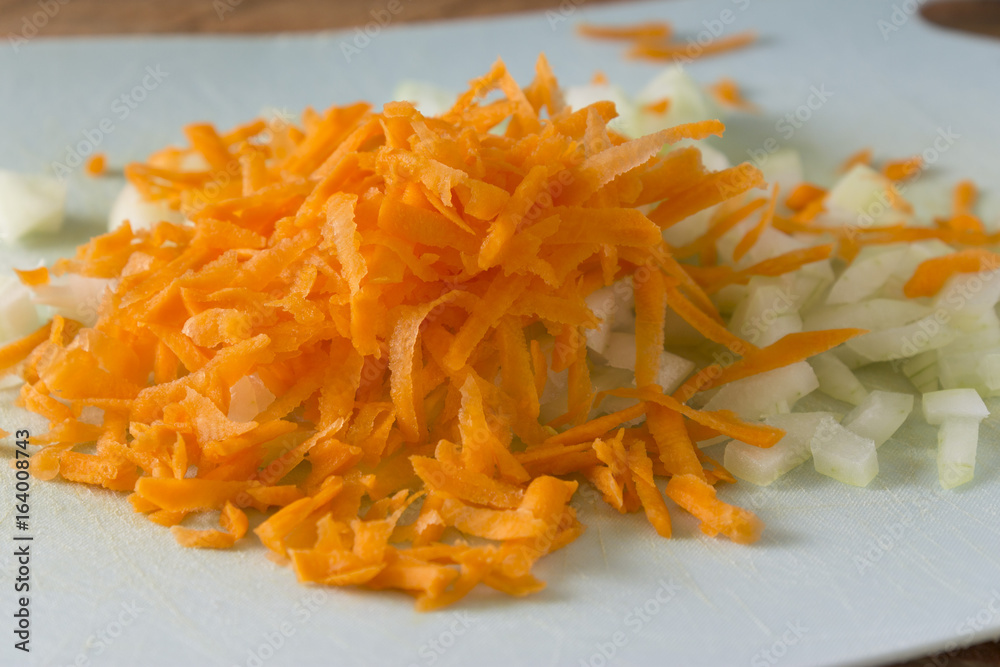 Grated carrots and chopped onions on a cutting board. Cooking homemade food. Healthy food. Grated carrots and chopped onions on a cutting board. Cooking homemade food. Healthy food.