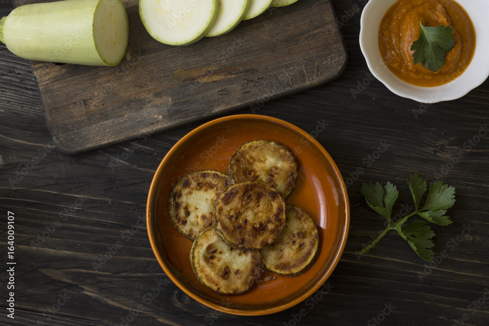 Fried zucchini in a clay bowl on a wooden table. Healthy food. Fried zucchini in a clay bowl on a wooden table. Healthy food.
