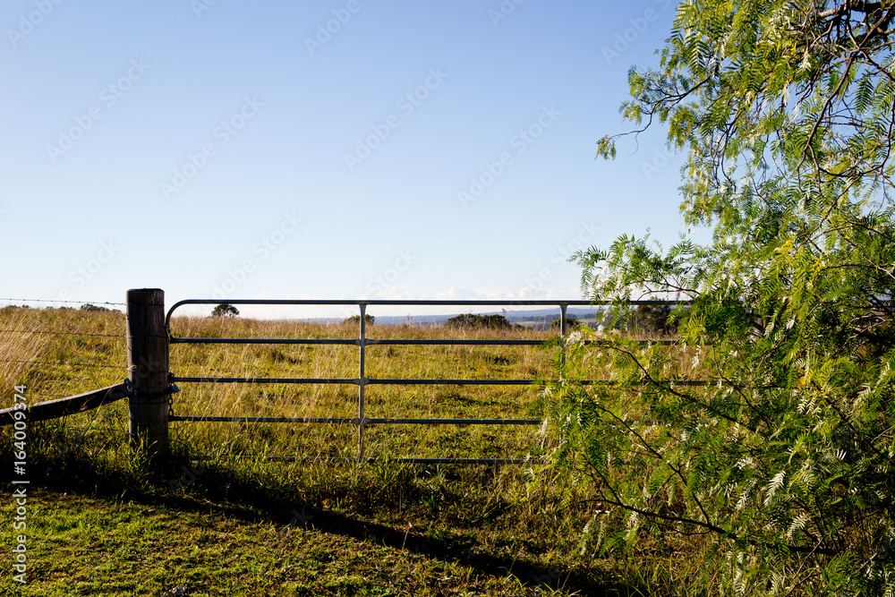 Metal gate and wooden fence post on  field on hill