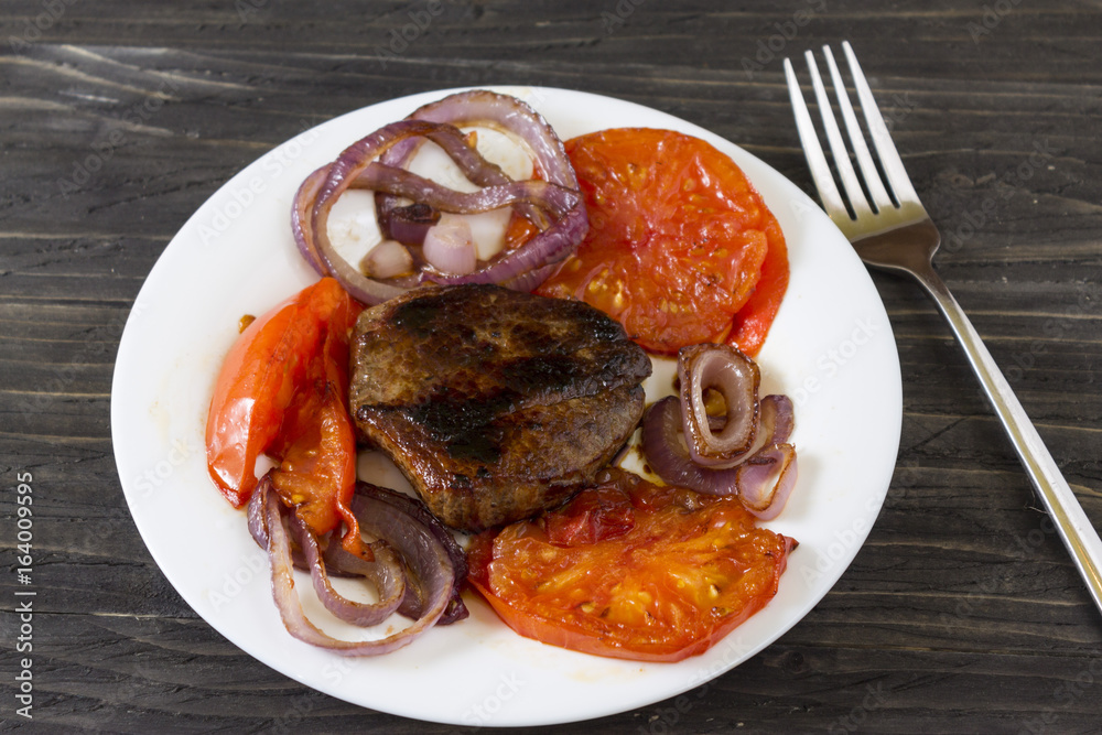 Fried meat with vegetables on a white plate. Tasty and nutritious dish. Fried meat with vegetables on a white plate. Tasty and nutritious dish.