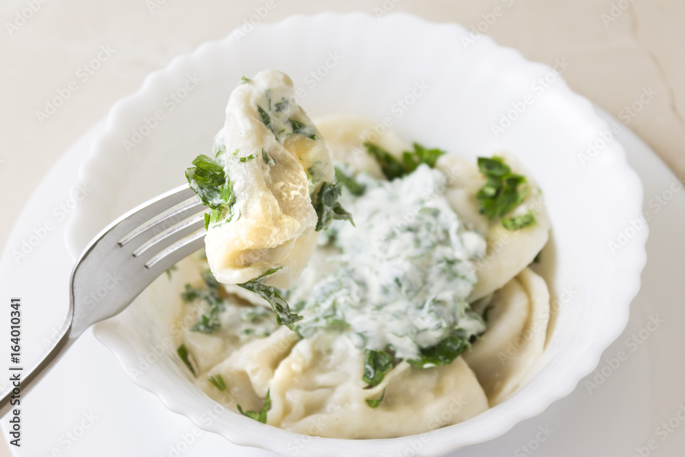 Homemade pelmeni or meat dumpling with sour cream and parsley. Traditional Russian cuisine. Homemade pelmeni or meat dumpling with sour cream and parsley. Traditional Russian cuisine.