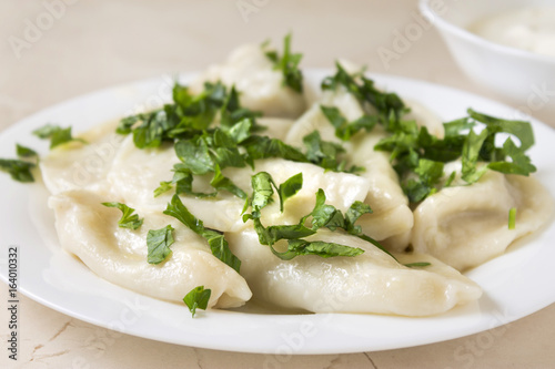 Homemade pelmeni or meat dumpling with sour cream and parsley. Traditional Russian cuisine.