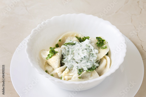 Homemade pelmeni or meat dumpling with sour cream and parsley. Traditional Russian cuisine.