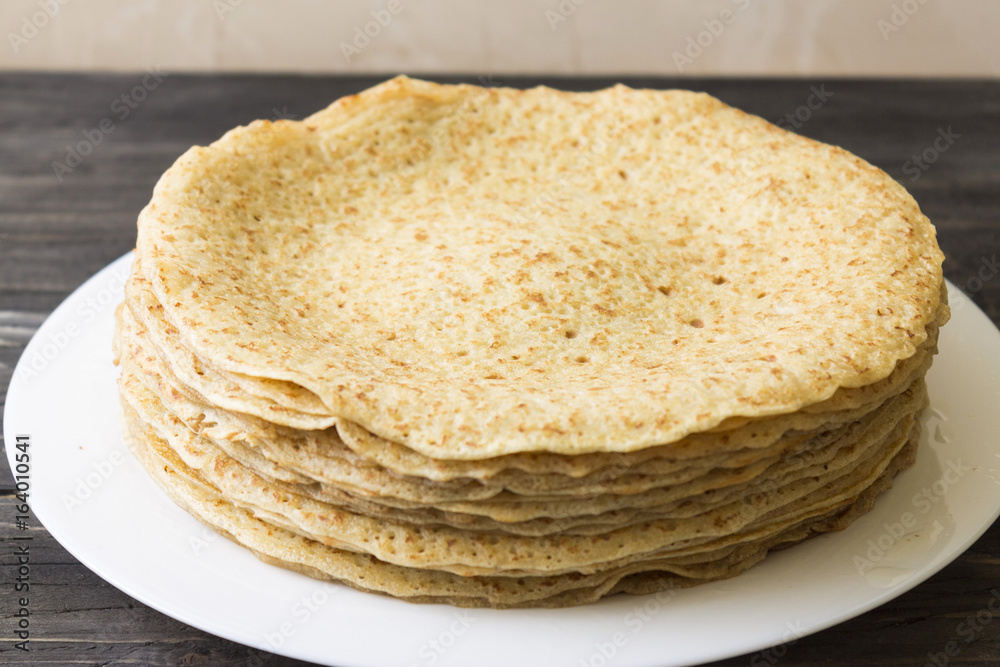 A pile of pancakes on a white plate. Delicious and nutritious breakfast.
