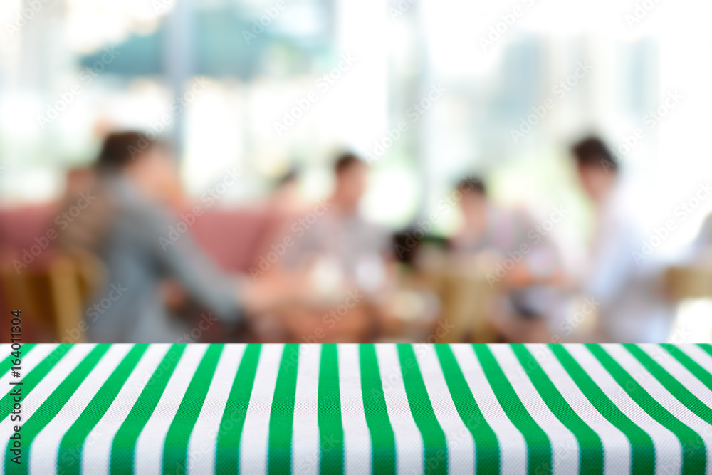 Table top covered with  stripped tablecloth on blurred background of people in cafe - can be used for montage and display foods or products