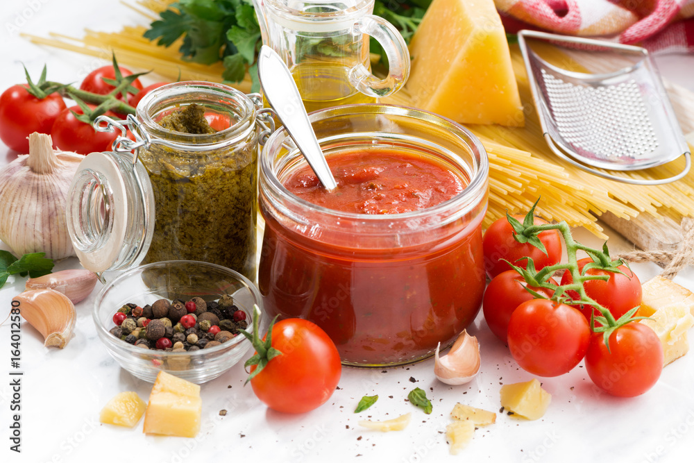 tomato sauce, pesto and ingredients for pasta on a white table, horizontal tomato sauce, pesto and ingredients for pasta on a white table, horizontal