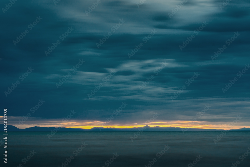 rippled surface of cold sea under sky with fluffy clouds at sunrise
