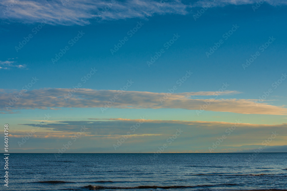 rippled surface of cold sea under sky with fluffy clouds at sunrise
