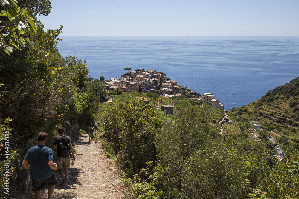 View of Corniglia village from the path on the hill and two travelers