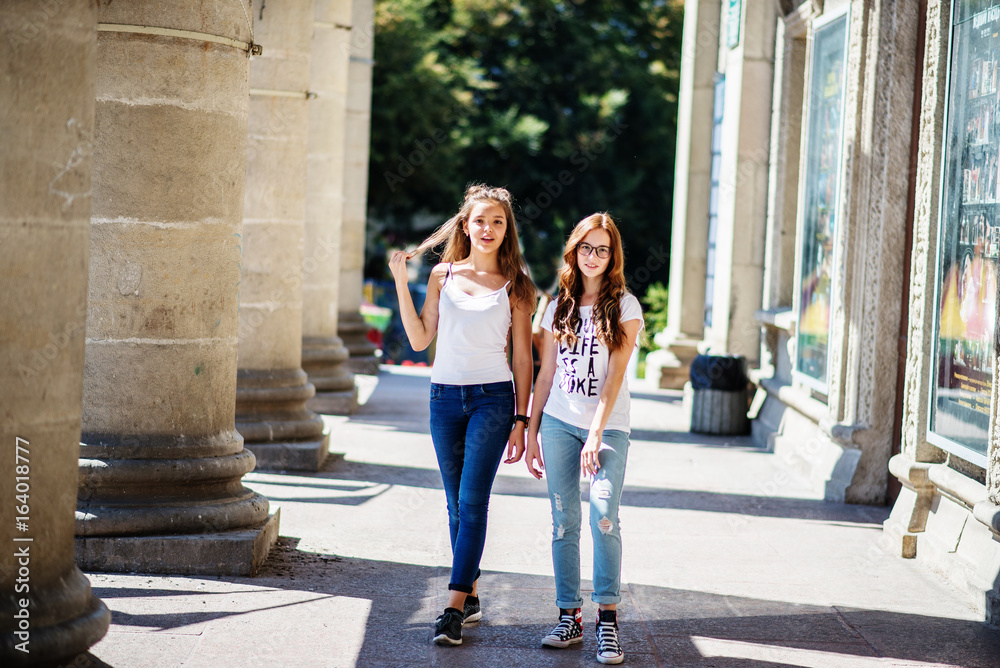Two young girls having fun standing next to the columns.