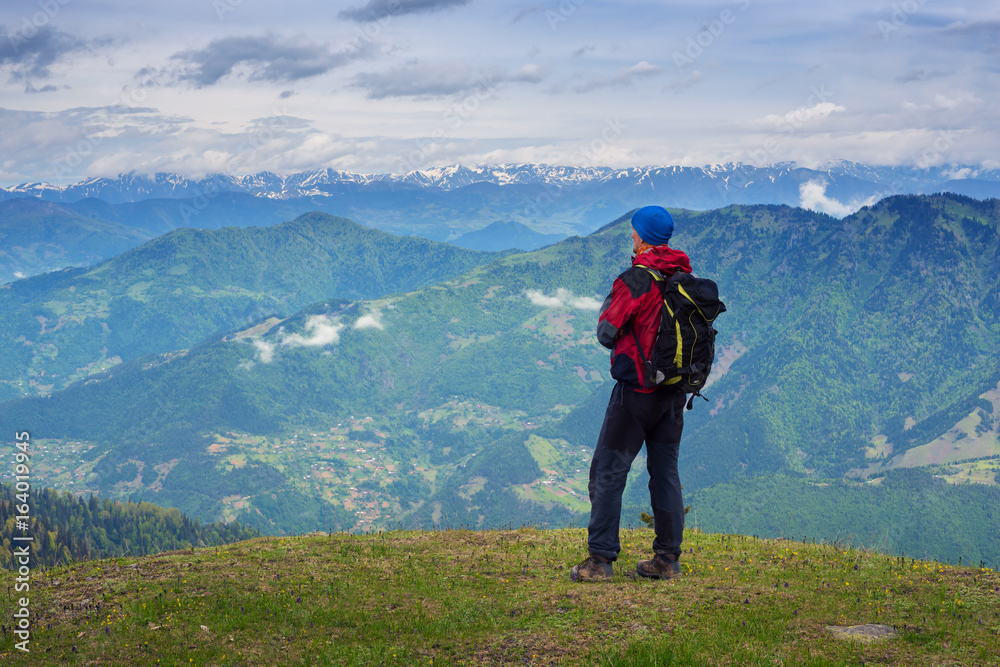 Man traveler admires a panorama of mountains Man traveler admires a panorama of mountains