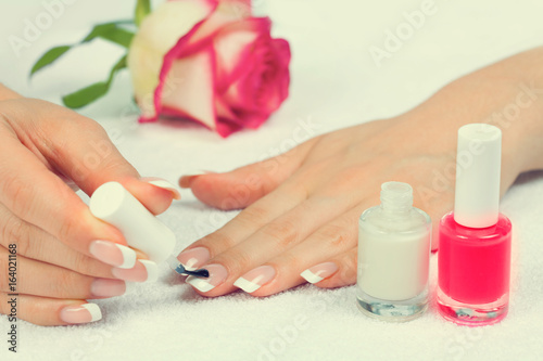 Woman applying nail polish for perfect french manicure on white towel