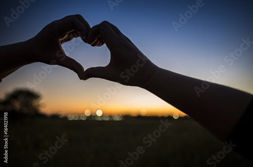 Lover hands making heart at sunset background