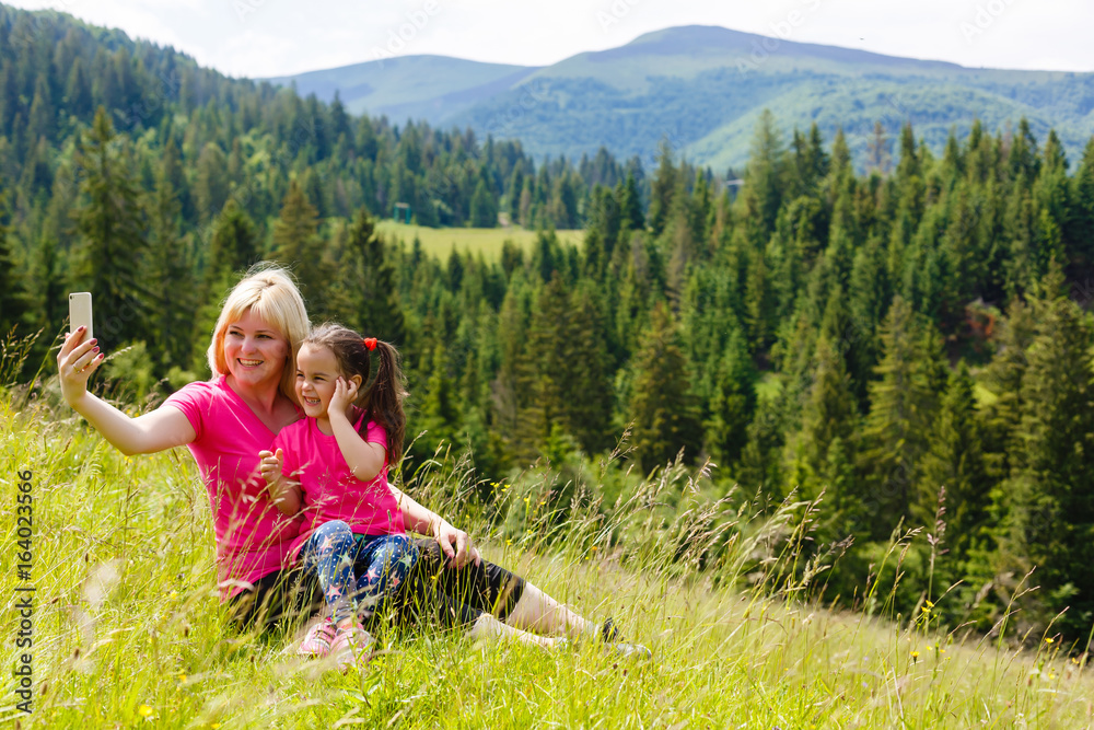 Mother and little daughter talking on the phone in the mountains