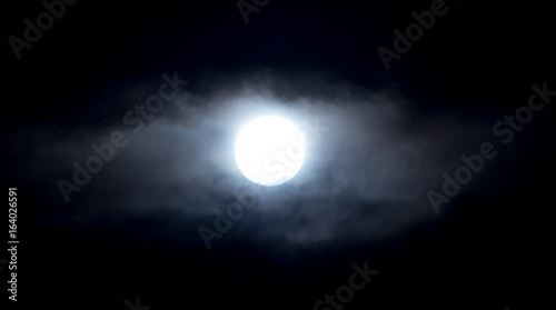 The moon in the haze of the clouds at night