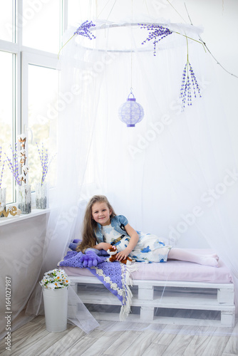 Happy child girl having fun at home near the window