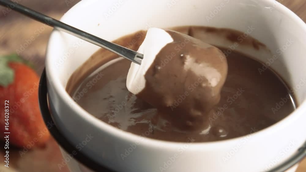 Fondue. Close-up marshmallow being dipped in chocolate Fondue. Close-up marshmallow being dipped in chocolate