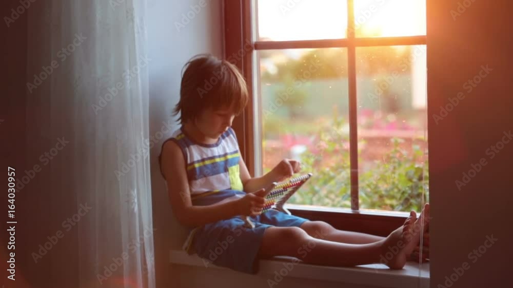 Cute little toddler child, playing with abacus on a window