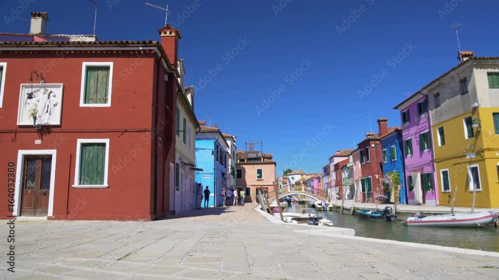 Cool view on colorful houses and Venetian canal, tourists relaxing in Burano Cool view on colorful houses and Venetian canal, tourists relaxing in Burano