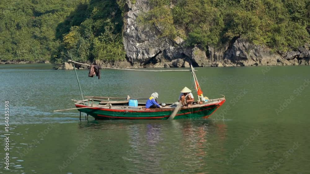 Vietnamese fishermen in the boat check their net at Ha Long Bay, Vietnam. Vietnamese fishermen in the boat check their net at Ha Long Bay, Vietnam.