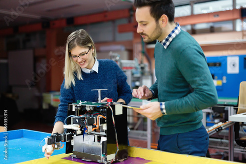 Young students of robotics preparing robot for testing