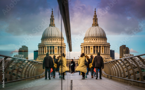 London, England - Londoners walking through Millennium Bridge. Reflecting St.Paul's Cathedral at background with beautiful colorful sky and clouds