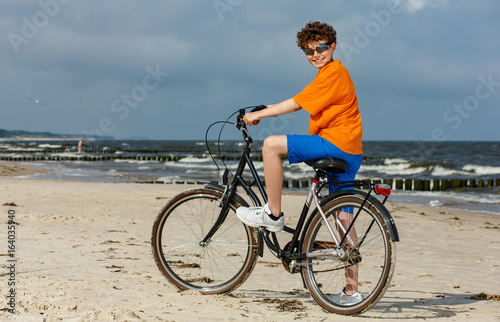 Teenage boy biking on beach 
