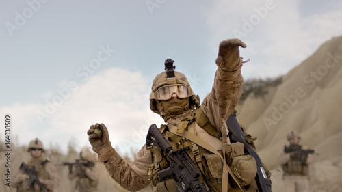 Soldier Throwing a Grenade during Combat in the Desert. photo