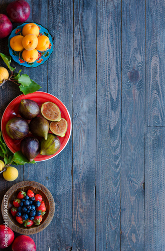 Fresh figs with peaches, apricots, blueberries, strawberries, on a wooden background.