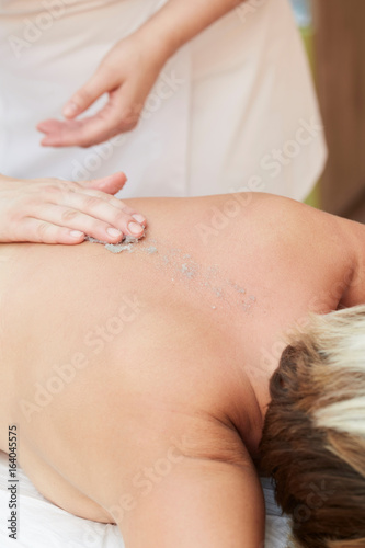 Beautiful blonde enjoying a salt scrub treatment at the health spa