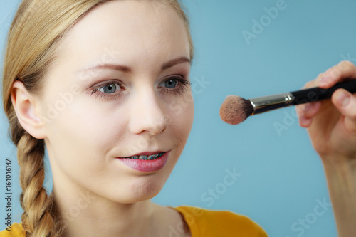 Makeup artist applying with brush rouge on female check