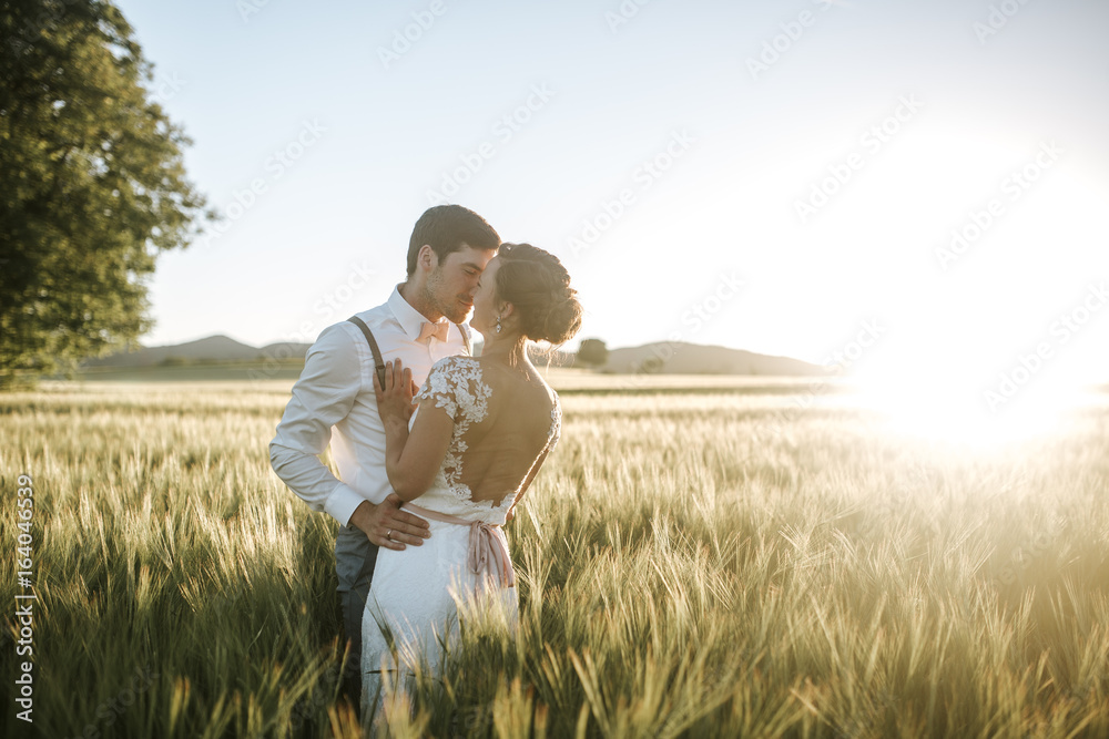 bride and groom standing in a field with sundown bride and groom standing in a field with sundown