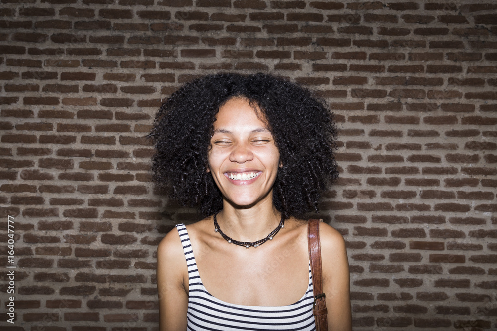 Portrait of smiling woman with eyes closed in front of brick wall Portrait of smiling woman with eyes closed in front of brick wall