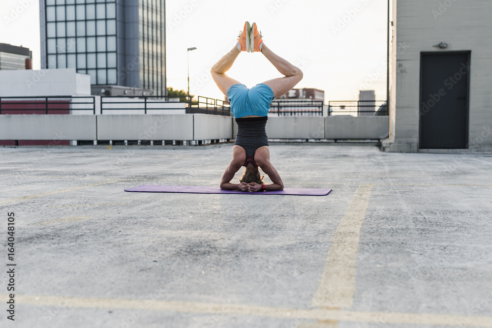 Woman doing a headstand on parking level in the city Woman doing a headstand on parking level in the city