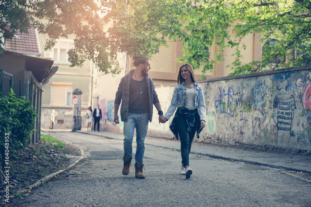 Couple holding hands outdoors. Young couple walking on the street.