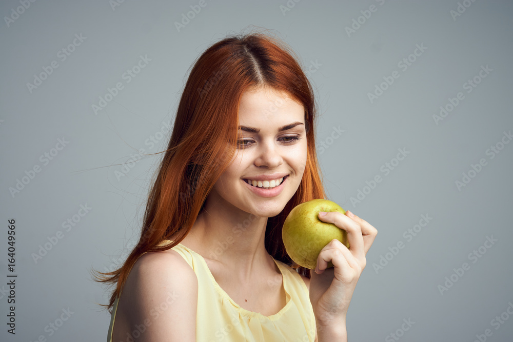 Beautiful young woman on a gray background holding an apple