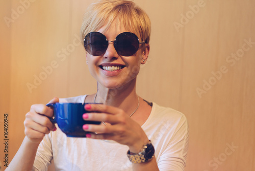 Girl smiling with coffee/ Beautiful girl smiling in sunny glasses with a big blue mug of coffee.